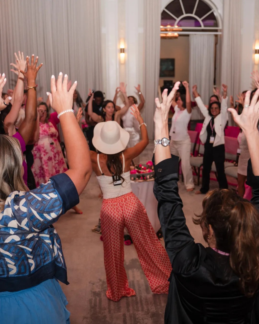 Women raising their hands together at Unleash Your Brave Live